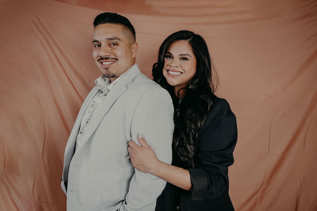 Couple in suits with salmon colored backdrop